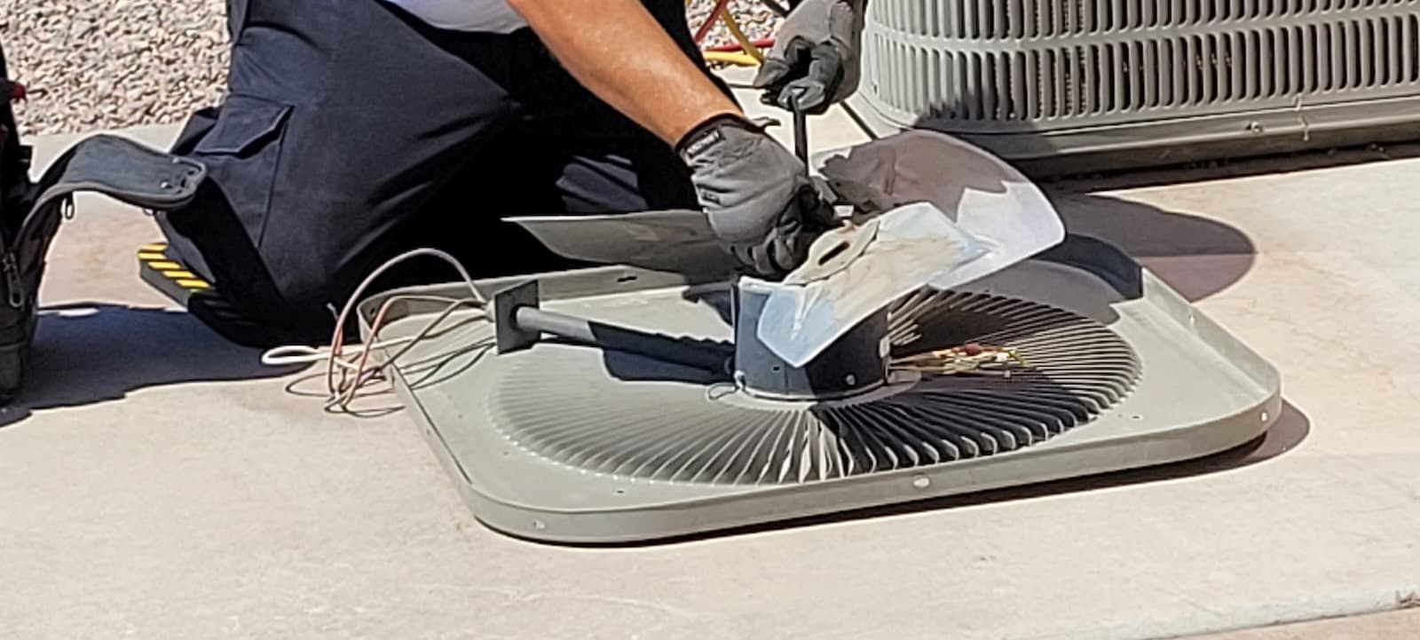 Technician servicing a condenser fan motor during an HVAC service visit